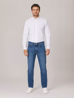 European male model wearing a white shirt, jeans and sneakers before the outfit change