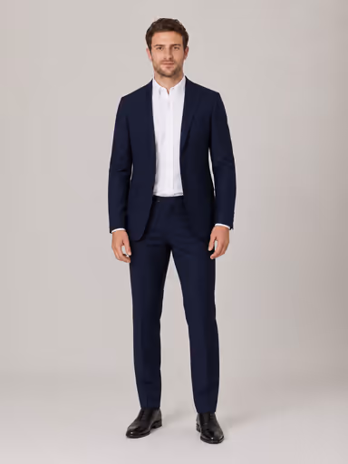 The same male model wearing the navy suit jacket, matching trousers and black leather shoes