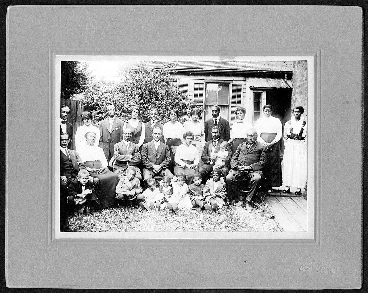 Before and after AI restoration of a circa-1920 family group photograph — Before